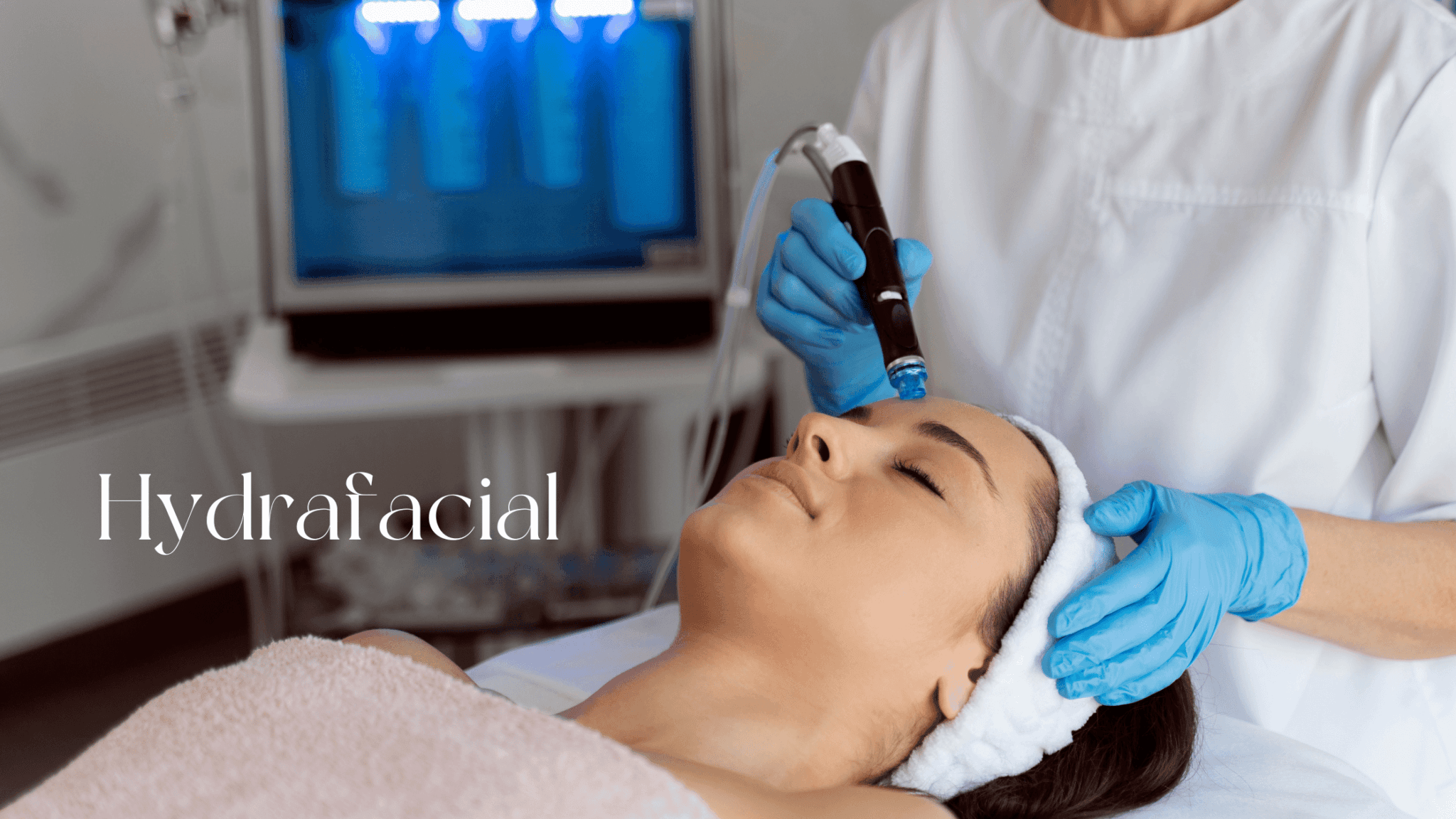 A beautician performs a HydraFacial treatment on a woman lying on a bed, with the HydraFacial device visible in the background. The image contains the text “Hydrafacial.”