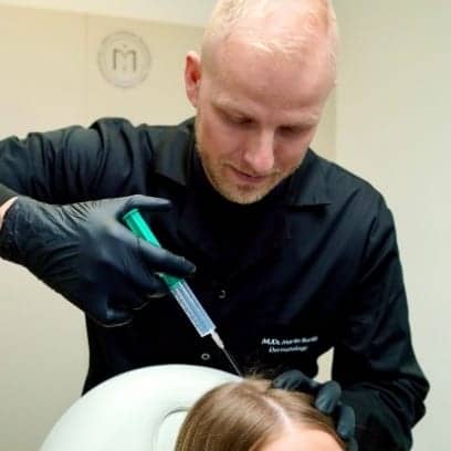 Dermatologist MUDr. Martin Bortlík injecting plasma into a woman’s scalp during plasma therapy to support hair growth.