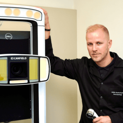 Dermatologist MUDr. Martin Bortlík from Skinity Clinic standing next to the IntelliStudio by Canfield device used for mole analysis and screening.